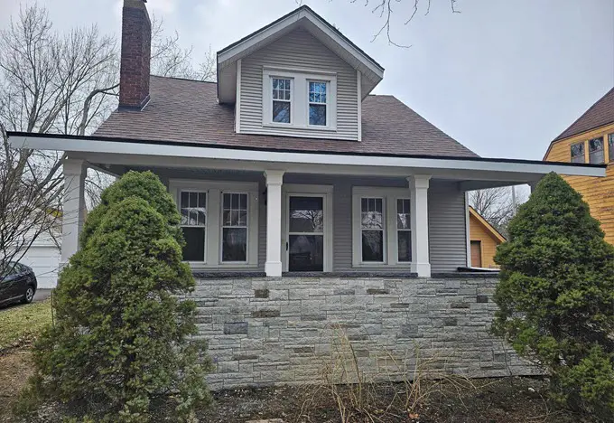 After view of a Traverse City home featuring new gray vinyl siding and Versetta stone porch accents installed by professional siding contractors.