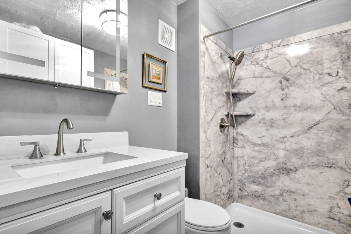 Completed Lansing, MI custom bathroom remodel featuring a Palisade tile walk-in shower, granite vanity top, and modern LED medicine cabinet.