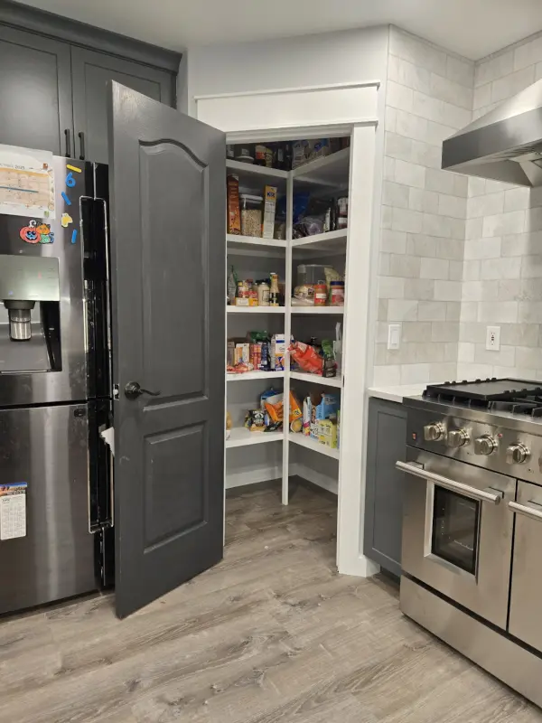 Custom walk-in pantry with white built-in wood shelving and grey door matching the kitchen renovation.