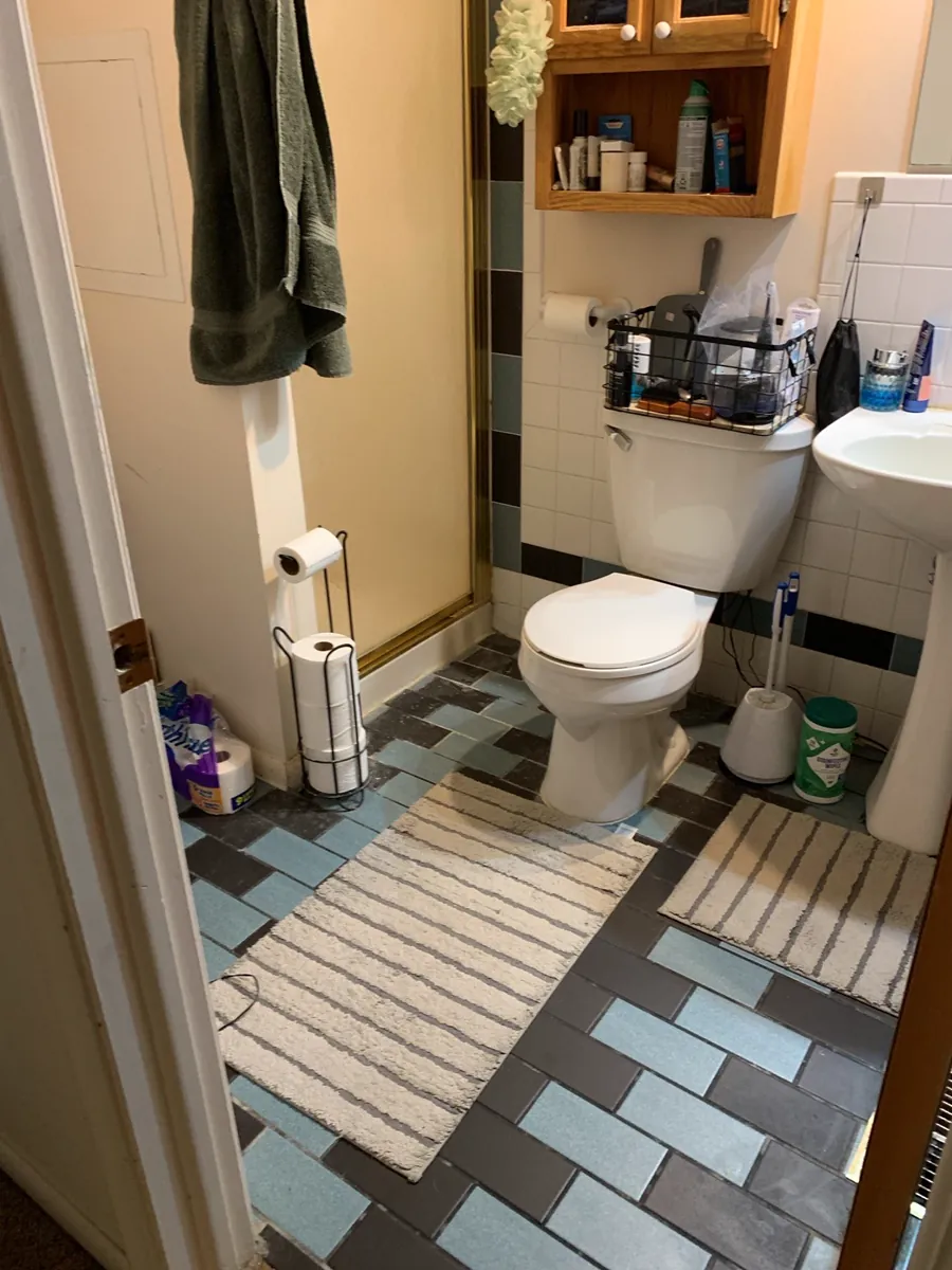 Dated blue and black ceramic tile flooring in West Michigan bathroom before remodel.