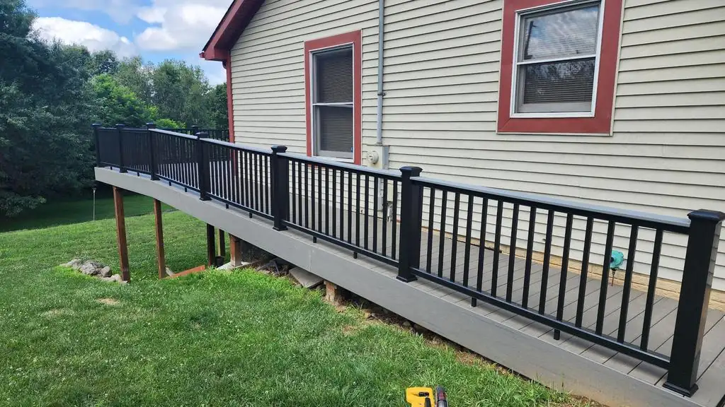 New grey TimberTech composite deck ramp with black aluminum railings in East Grand Rapids.