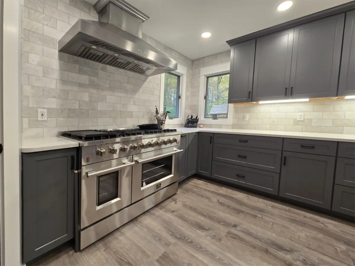 Renovated kitchen corner with new luxury vinyl plank flooring, under-cabinet lighting, and quartz countertops.