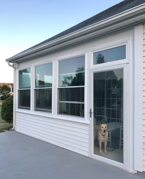 A white vinyl sunroom with large Soft-Lite replacement windows and a patio door on a Lansing, Michigan home.