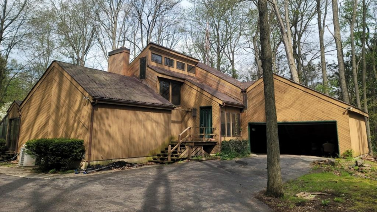 "Before" image of a home in Brighton, Michigan, with weathered brown wood siding, prior to a James Hardie fiber cement siding replacement.