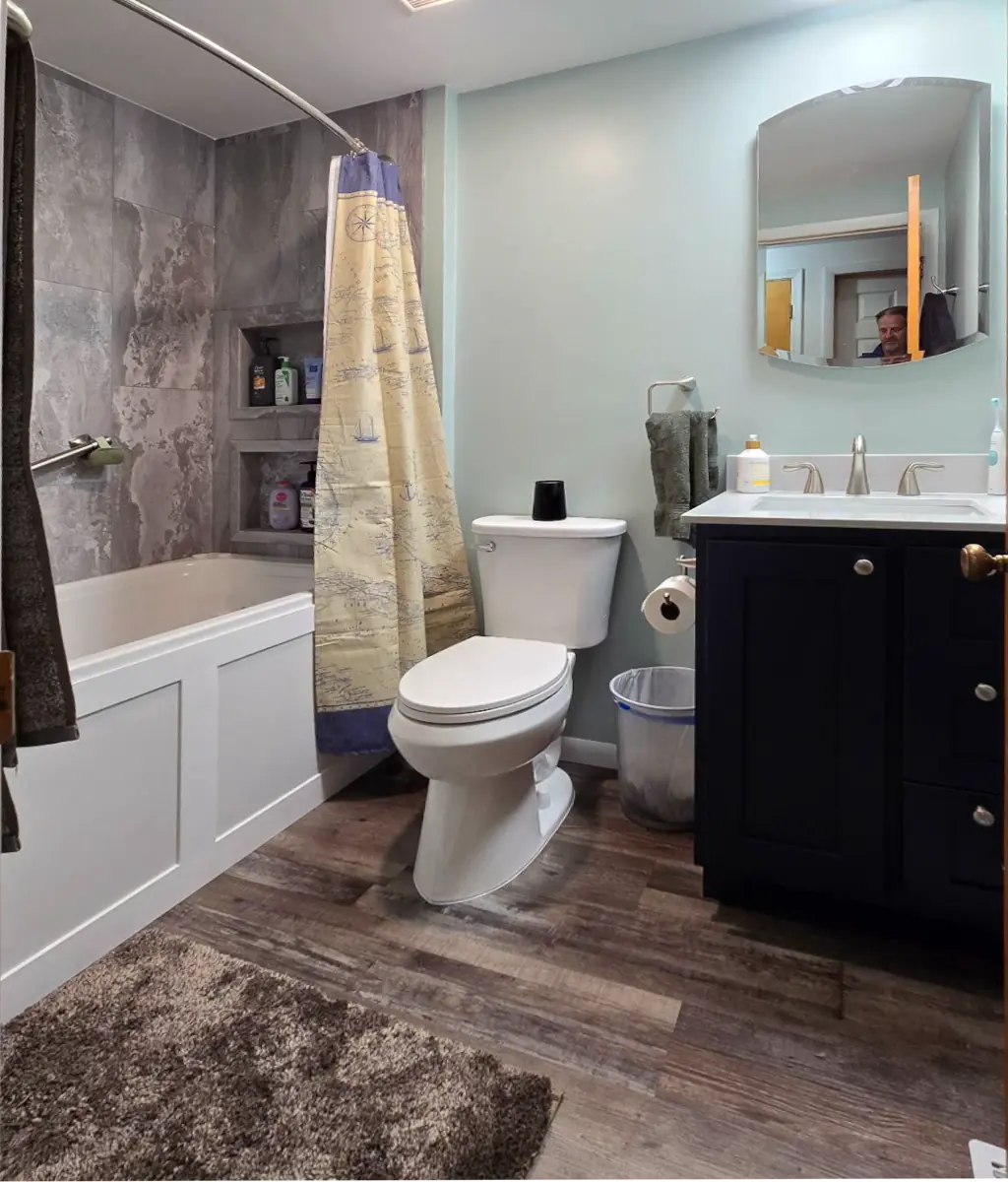 Waterproof luxury vinyl plank flooring and navy vanity in Grand Rapids bathroom remodel.