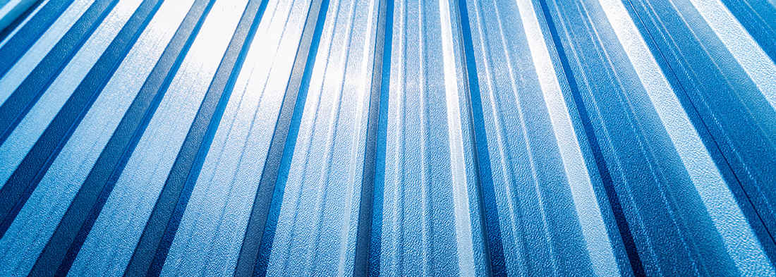 A close-up texture shot of blue metal roofing panels, a material used for roof installation on homes in Lansing, Michigan.