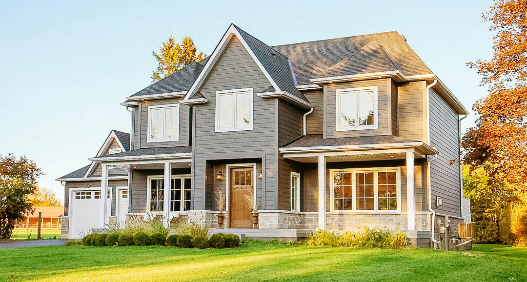 A large two-story gray house with James Hardie siding and new white replacement windows in Lansing, Michigan.
