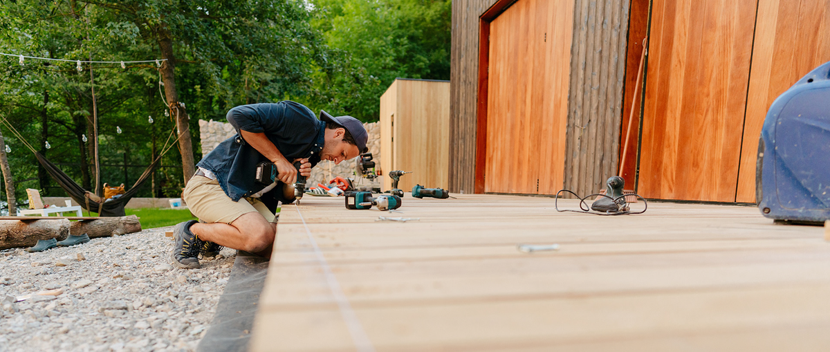 A contractor kneels to install light-colored Trex composite decking at a modern home in Lansing, Michigan.