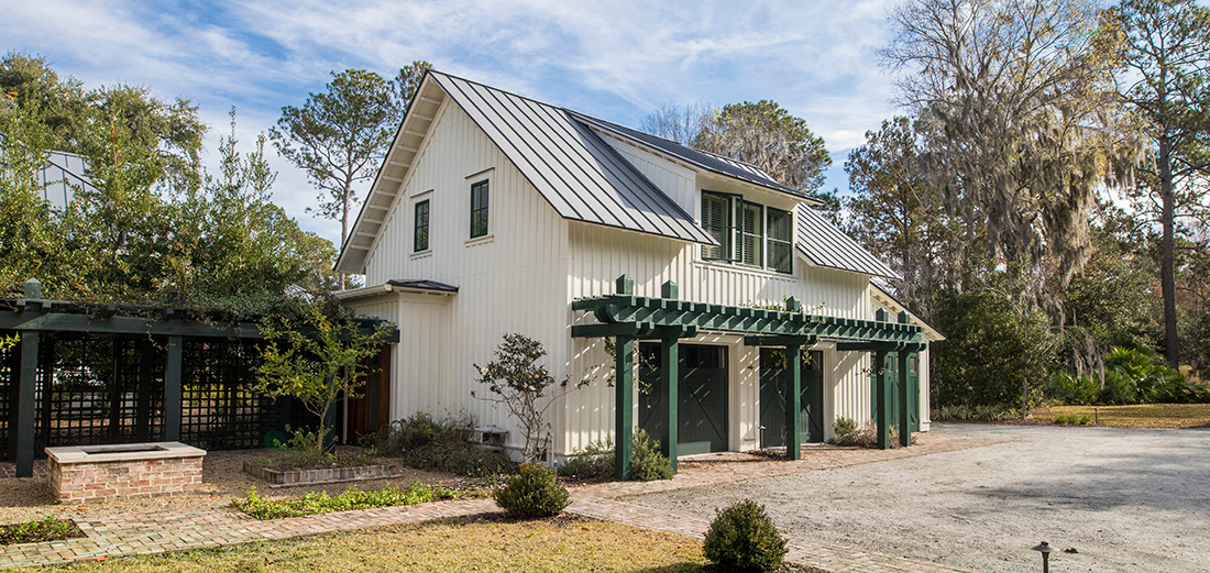 A white farmhouse in Ada Township, Michigan, featuring a new black standing-seam metal roof, and white vertical siding.