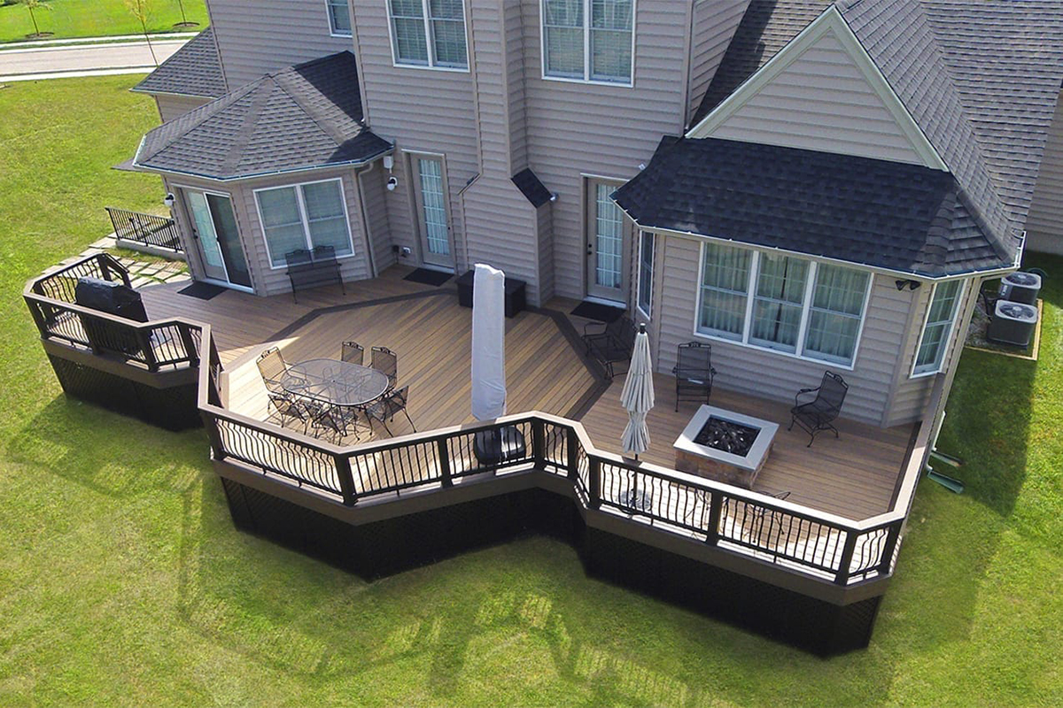 Aerial view of a large, brown TimberTech composite deck in Ada Township, Michigan, featuring a distinct octagon section with a fire pit and a separate area for a grill.
