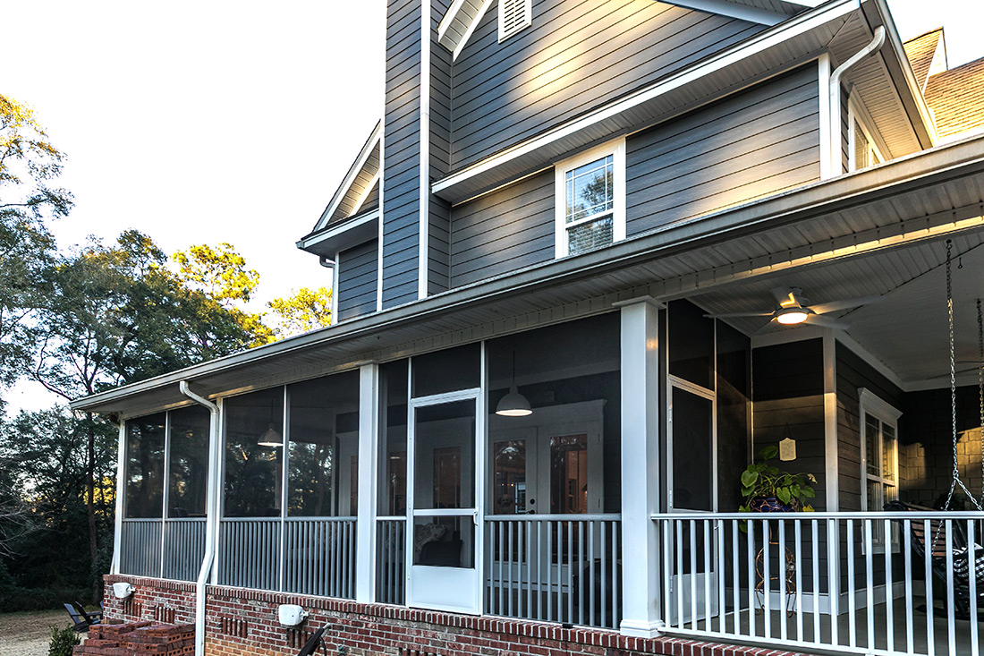 A home in Ada Township, Michigan, featuring dark grey James Hardie fiber cement siding, new Home Depot windows, and a large screened-in porch.