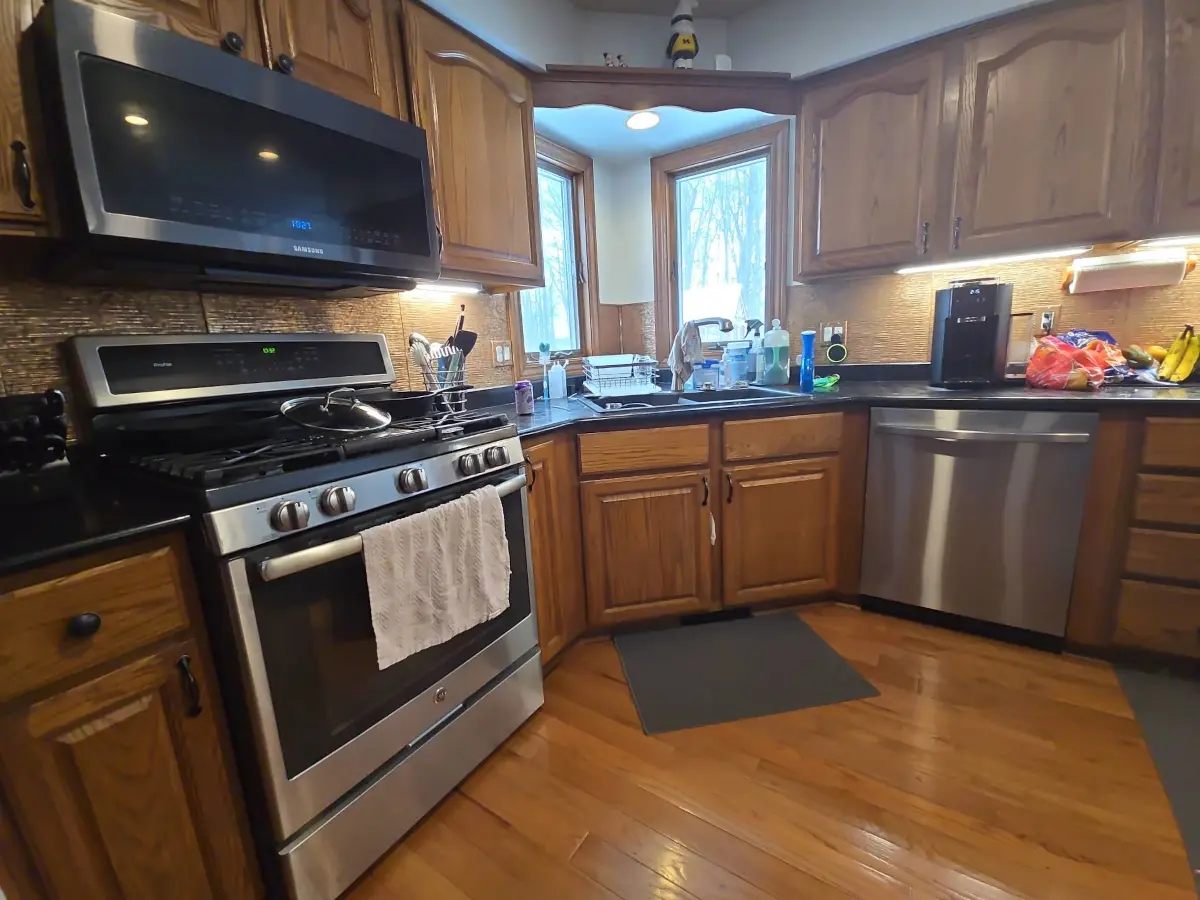 Old kitchen corner showing cluttered dark countertops and original flooring.
