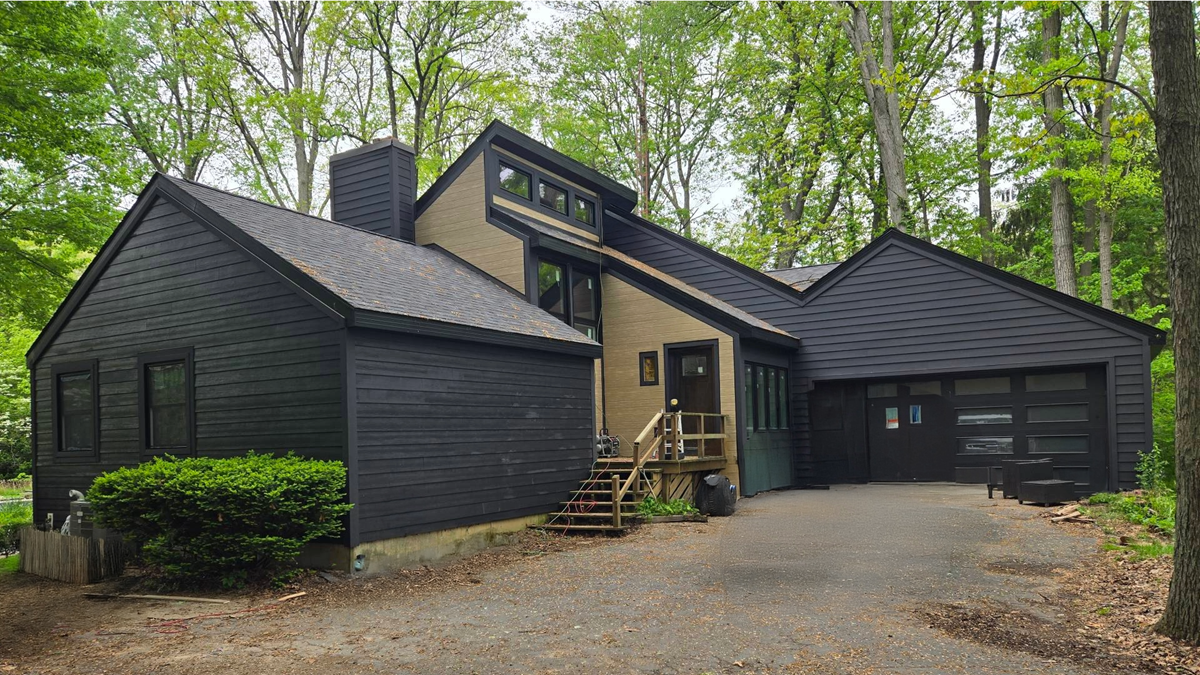 "After" image of a home in Brighton, Michigan, featuring new dark gray James Hardie fiber cement siding installed by siding contractors.