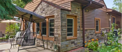 After photo of a completely remodeled home in Ada, Michigan, showcasing new Versetta Stone accent walls, Certainteed Monogram Cedar Shake shingles on the gable, Certainteed Monogram vinyl siding, enhancing the home's exterior.