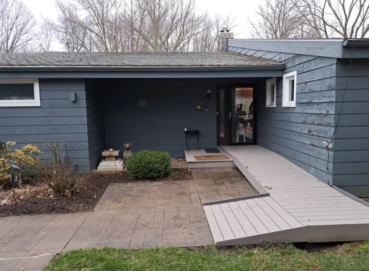 The front entrance of a Mason, MI home showing peeling blue wood siding before its Hardie siding and Versetta stone renovation.