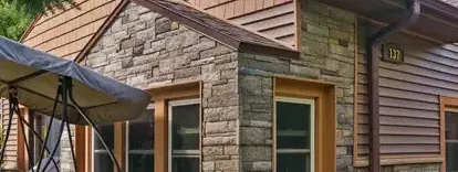 After photo of a completely remodeled home in Lansing, Michigan, showcasing new Versetta Stone accent walls, Certainteed Monogram Cedar Shake shingles on the gable, Certainteed Monogram vinyl siding, enhancing the home's exterior.