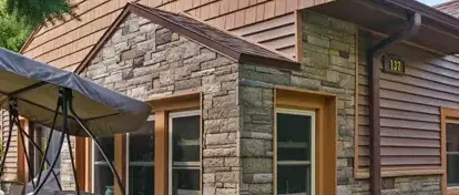 After photo of a completely remodeled home in Lansing, Michigan, showcasing new Versetta Stone accent walls, Certainteed Monogram Cedar Shake shingles on the gable, Certainteed Monogram vinyl siding, enhancing the home's exterior.